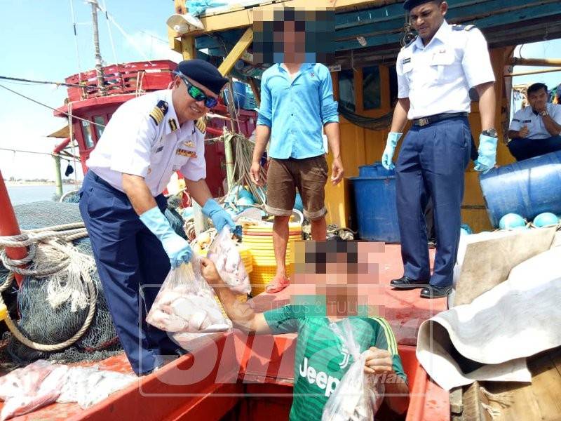 Muhammad Suffi (kiri) menunjukkan sebahagian hasil tangkapan laut yang dirampas daripada kedua-dua bot ditahan.