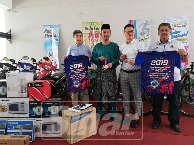 Azmi (dua, kiri) menunjukkan antara hadiah yang bakal menanti peserta dalam acara larian sempena program Sultan Ismail Bridge International Challenge 2019. 
