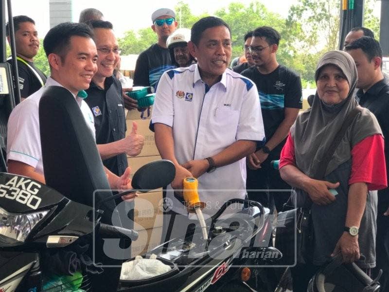 Muez mengisikan minyak pada motosikal milik Roziah Hassan, 59 (kanan) di Stesen Minyak Petronas Seri Iskandar.