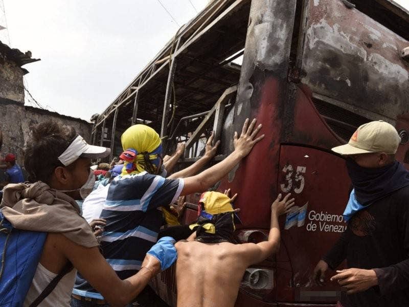 Penunjuk perasaan Venezuela menolak sebuah bas yang dibakar ketika protes di bandar Urena, Tachira, selepas Presiden Maduro umum penutupan sementara sempadan dengan Colombia.- Foto AFP
