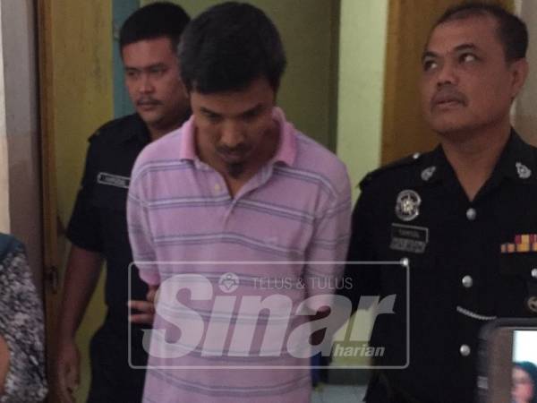 Mohd Irwan (tengah) diiringi polis ketika perbicaraan.