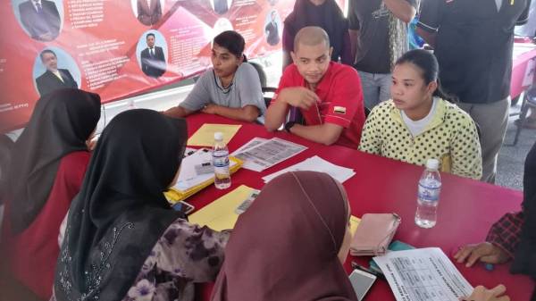 Hasnul Zulkarnain (tengah) menyantuni penduduk di pejabat Pusat Khidmat ADUN Titi Serong hari ini.