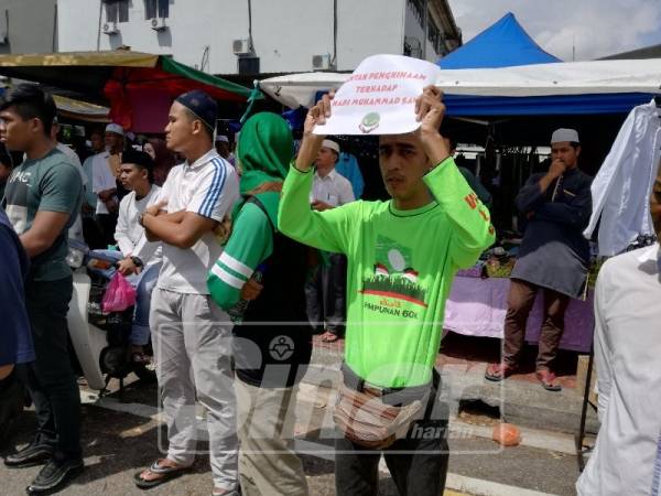Salah seorang peserta memegang kertas bantahan pada himpunan itu.