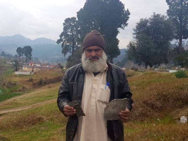 Fida Hussein, 46, memegang serpihan bom yang dibedil tentera India di perkampungan Jaba di Pakistan.