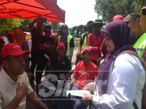 
Petugas SPR menerangkan peraturan pilihanraya kepada penyokong PH mengenai kain rentang Provokasi yang digantung di Kampung Sesapan Batu Rembau hari ini.- Foto Sinar Harian/SHARIFUDIN ABDUL RAHIM
