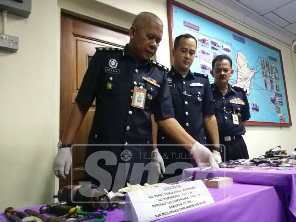 Mohd Zani (kiri) menunjukkan antara peralatan yang dirampas.