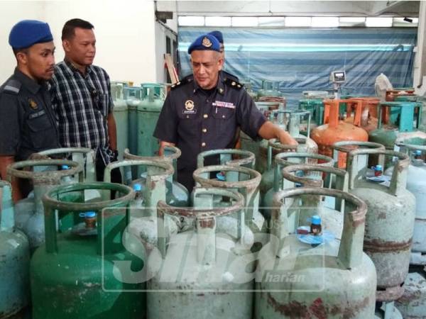 Basaruddin (kanan) melihat sebahagian tong LPG yang dirampas dalam serbuan di sebuah premis di Jalan Teruntum 12, petang semalam.