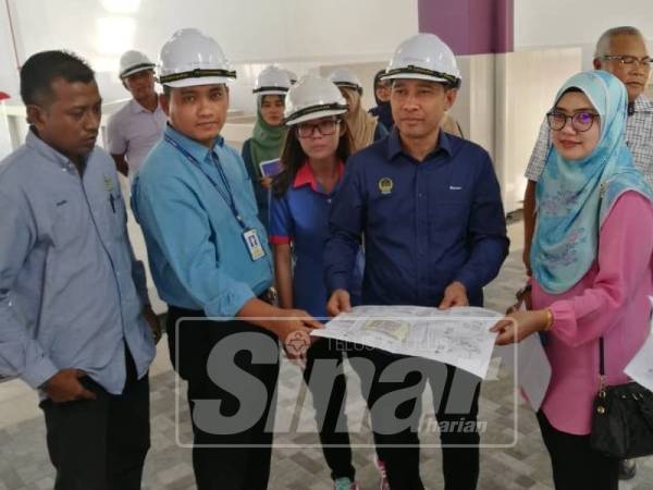 Abdul Yunus(dua kanan) dan Norhafisah(kanan) meninjau pelan pembinaan pasar awam Tanjung Piandang sewaktu mengadakan lawatan kerja ke lokasi itu di Taman Piandang Indah, Tanjung Piandang petang tadi.