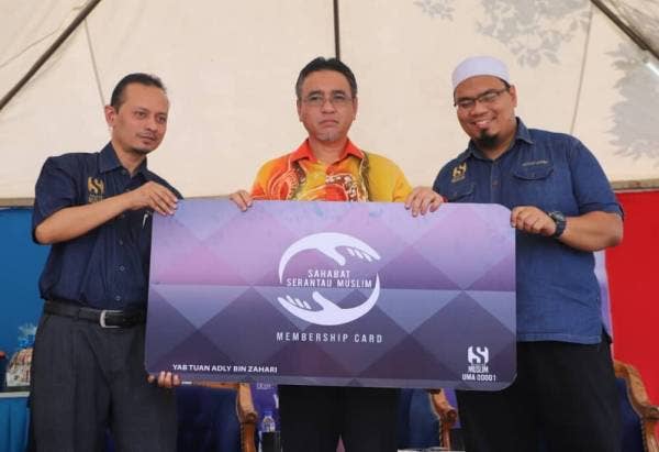 Adly (tengah) memegang replika kad keahlian SM ketika merasmikan Pejabat Operasi Serantau Muslim (SM) serta program Kembara Prihatin dan Sahabat SM di Taman Seri Telok Mas, di sini, hari ini.