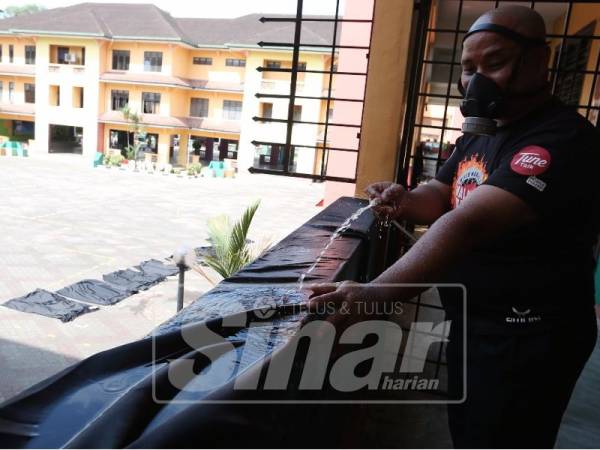 Salah seorang sukarelawan ketika membersihkan fabrik di Sekolah Menengah Kebangsaan Taman Pasir Putih, hari ini.