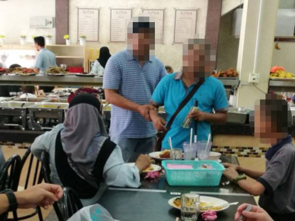 Seorang lelaki (kiri) mengiringi seorang OKU ketika meminta sedekah di sebuah restoran.