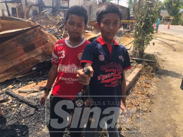 Mukriz Aiman (kiri) bersama rakan menunjukkan itik yang hangus dalam kejadian itu.