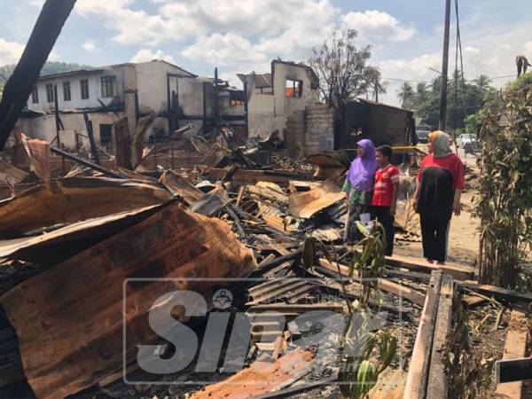 Raziah (kiri), Mukriz Aiman dan Mariah melihat sisa kebakaran rumah mereka.