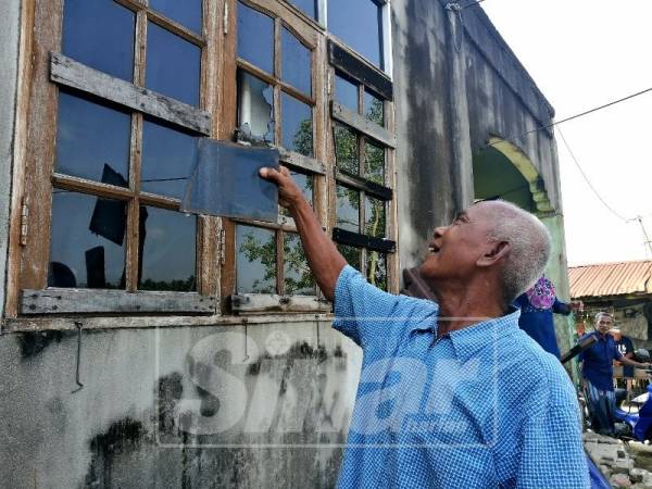 Abdul Manaf menunjukkan cermin tingkap rumahnya pecah.