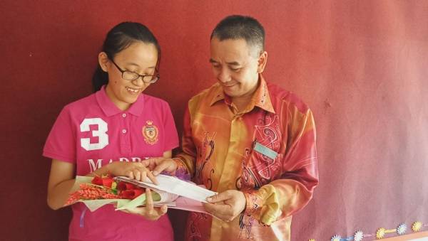 Xin Ci menunjukkan keputusan cemerlangnya kepada bapa.