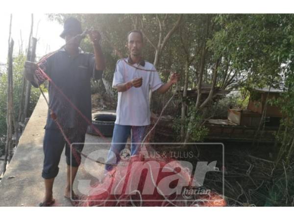 Nelayan menunjukkan pukat mereka yang rosak.