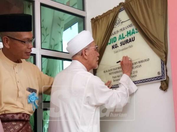Mohamad Shukri menandatangani plak perasmian Masjid Al Hassan hari ini.