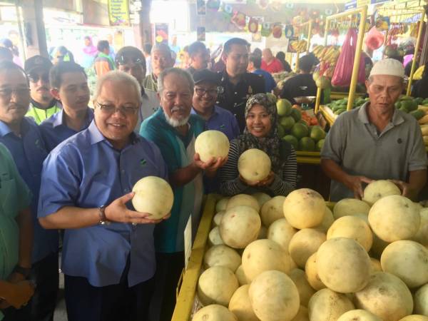 Ishak (hadapan) melihat buah-buahan di GBBS Teluk Intan semasa lawatan kerjanya.
