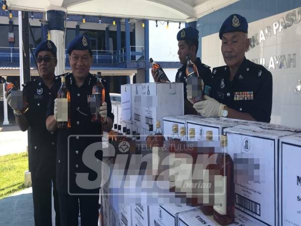 Paul menunjukkan minuman keras berjenama yang dirampas.