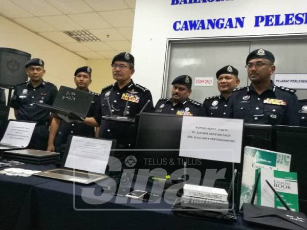 Mazlan (tiga, kiri) menunjukkan komputer riba yang dirampas. 