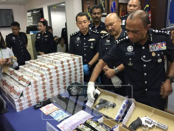 Mohd Khalil menunjukkan pistol yang dirampas.