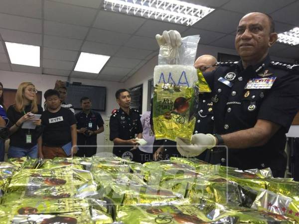 Mohd Khalil menunjukkan dadah yang dirampas.