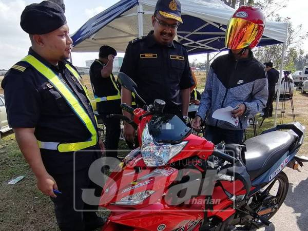 Muhammad Firdaus (tengah) menunjukkan kesalahan tidak memakai topi keledar dalam kalangan penunggang motosikal di negeri ini.