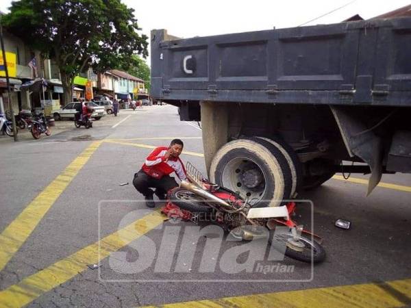 Muhammad Nor Azmi melihat motosikalnya yang digilis sebuah lori dalam kejadian petang semalam.