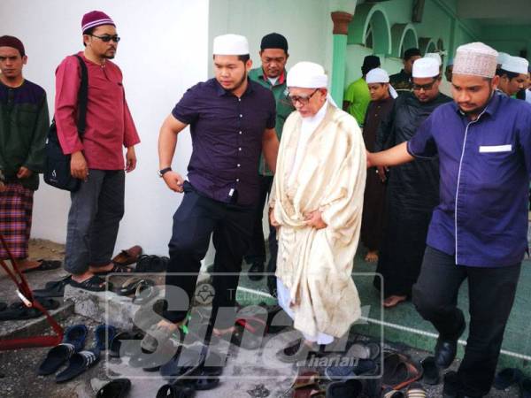 Abdul Hadi diiringi petugas keluar dari Masjid Rusila selepas berakhirnya kuliah di masjid itu, hari ini.
