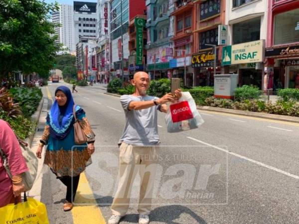 Cik Yon mengambil kesempatan bergambar di laluan kenderaan yang lengang susulan penutupan sebahagian Jalan TAR.