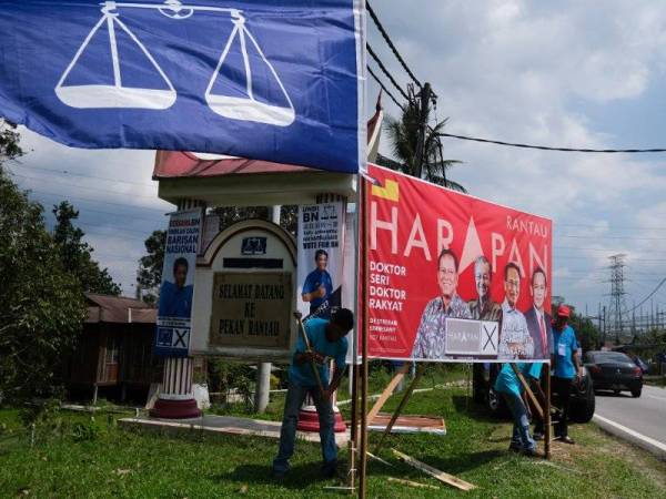 Petugas PH dilihat memasang poster kempen yang tertera gambar calon PH Dr S Streram, berhampiran papan tanda 'Selamat Datang Ke Rantau' sempena tempoh berkempen PRK DUN N27 Rantau. Turut kelihatan bendera poster calon BN Datuk Seri Mohamad Hasan turut dipasang ditempat yang sama. -Foto Bernama