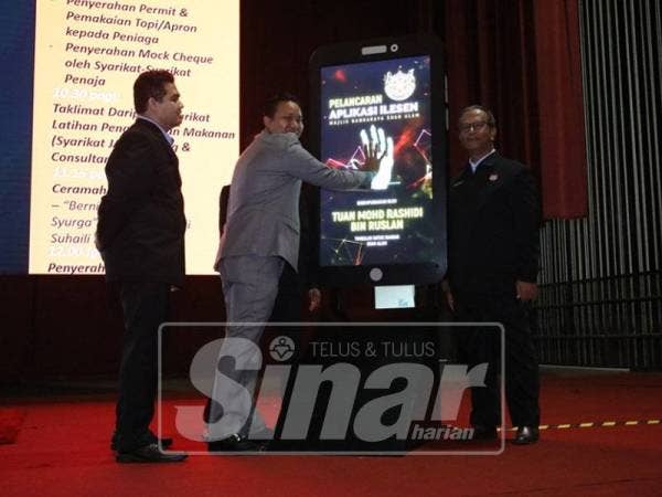 Mohd Rashidi (tengah) melakukan gimik pelancaran i-Lesen iaitu aplikasi permohonan lesen secara online yanag dibangunkan MBSA.
