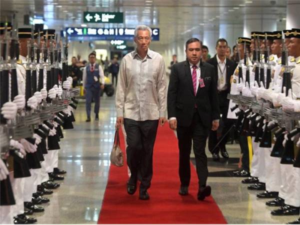 Lee Hsien Loong (depan, kiri) diiringi Menteri Pengangkutan selaku Menteri Pengiring Anthony Loke Siew Fook (depan, kanan) melintasi Kawalan Kehormat Setempat Batalion Pertama Rejimen Renjer DiRaja sejurus tiba di Lapangan Terbang Antarabangsa Kuala Lumpur (KLIA) hari ini. - Foto Bernama
