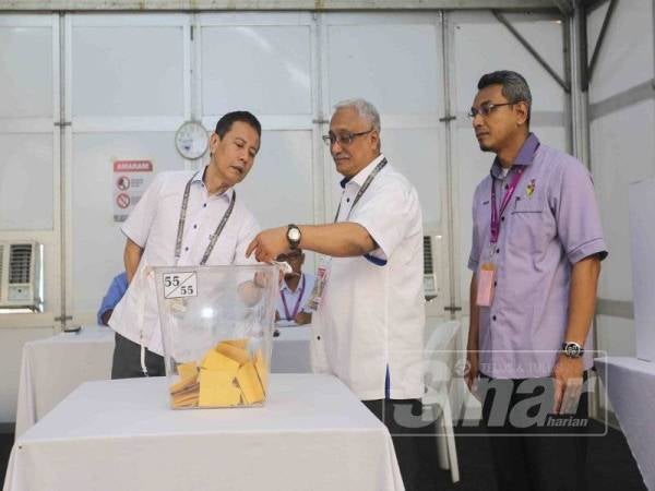 Azhar (kiri) ketika melawat pusat pengundian awal di Balai Polis Rantau di sini, hari ini. - ADAM AMIR HAMZAH