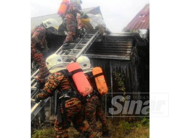 Anggota bomba BBP Kuala Kurau sedang berusaha menurunkan mayat mangsa dari bumbung rumahnya dengan menggunakan alat pengusung di Jalan Pantai Kuala Kurau, pagi tadi.