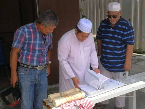 Pengurusan masjid memeriksa rekod kematian bagi mengenal pasti asal batu nisan itu