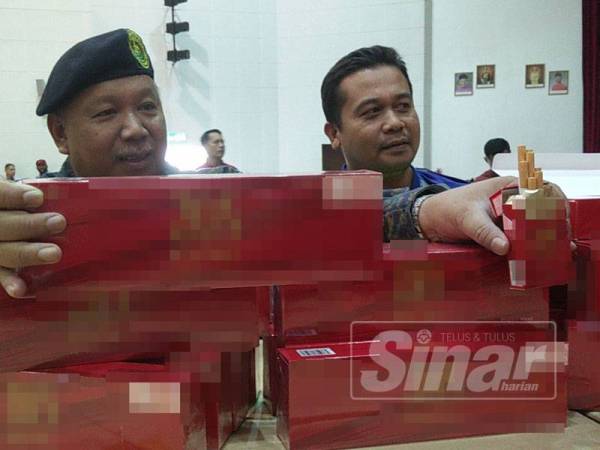 Abdul Latif (kiri) menunjukkan rokok dirampas pada sidang media di Kompleks KDN Anak Bukit.