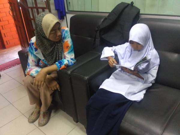 Umi (kiri) yang tidak melihat dengan sempurna sentiasa membimbing Marlis untuk membaca.