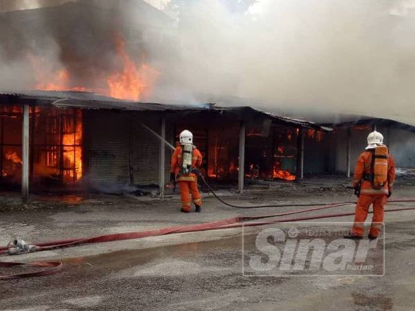 Anggota bomba memadamkan kebakaran membabitkan 11 gerai di Jalan Pasar, hari ini.