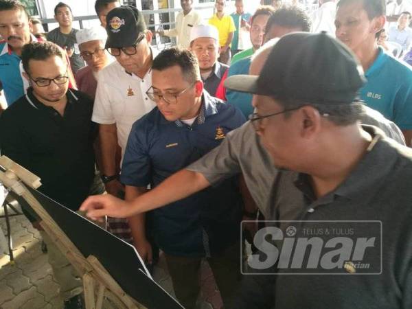 Amirudin melihat lakaran projek jejambat yang akan dibina dalam sesi lawatan di Bandar Saujana Putra.