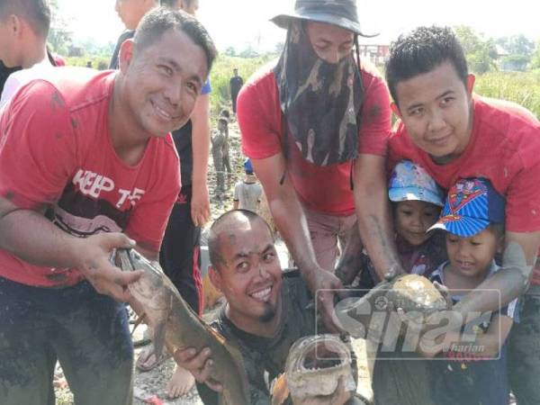 Peserta 'mengambat' ikan menunjukkan ikan yang berjaya ditangkap.
