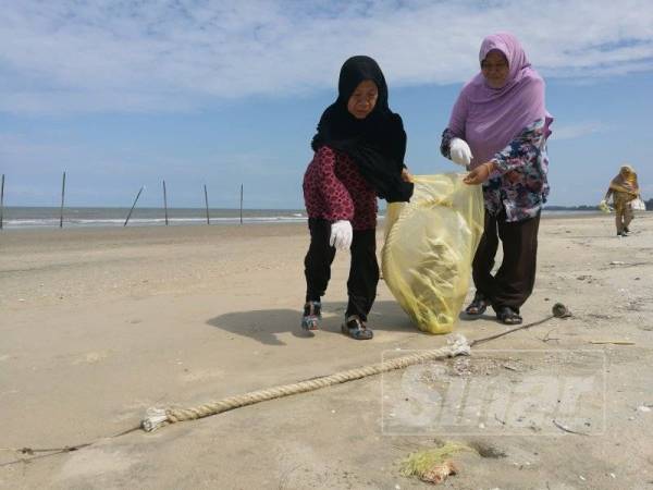Natrah (kanan) bersama Khatijah mengambil pendekatan bersama turun padang membersihkan kawasan Pantai Kempadang bagi memastikan pantai tersebut sentiasa dalam keadaan bersih.