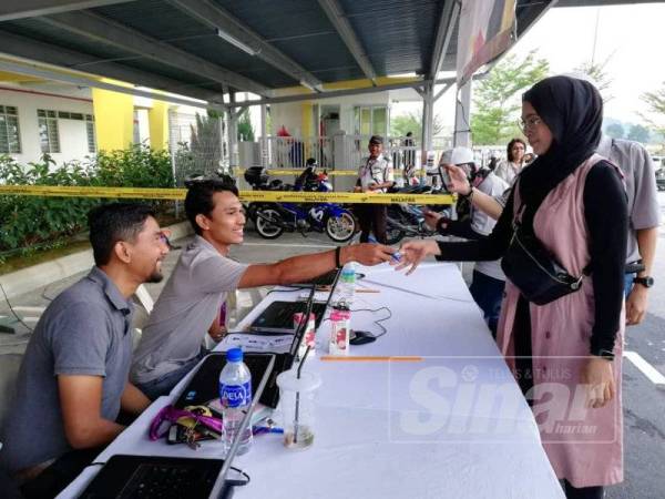 Siti Nordiana memeriksa maklumat pengundian di SJK (T) Bandar Sri Sendayan hari ini.