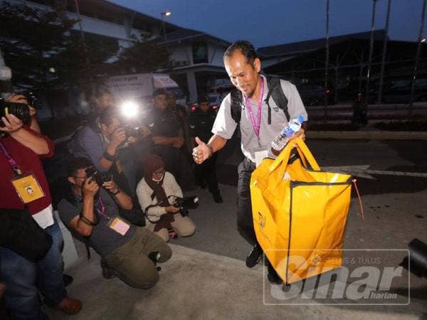 Pegawai Suruhanjaya Pilihan Raya (SPR) membawa kotak undi tiba dari pusat mengundi di SJKC Bandar Sri Sendayan hari ini.