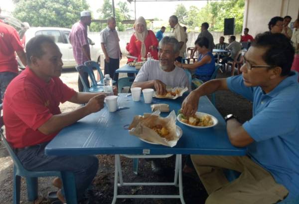 Pengerusi Majlis Pengurusan Komuniti Kampung (MPKK) Pedu, Arun a/l Sakwang (kiri) bertanya khabar penduduk yang hadir pada jamuan makan, semalam.