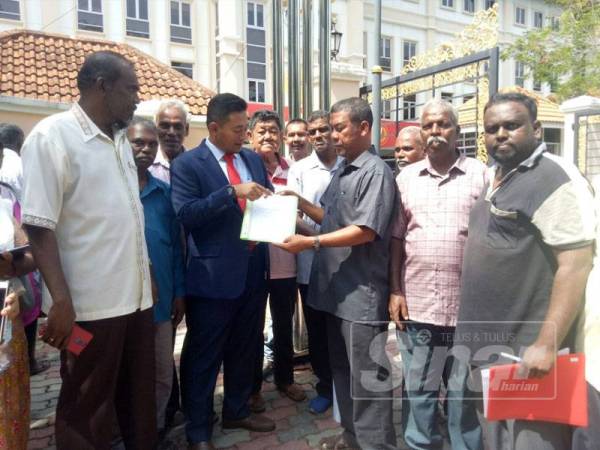 Anas Hafiz (empat dari kiri) menerangkan sesuatu kepada bekas pekerja Ladang Padang Meha di hadapan pintu masuk Wisma Darul Amam,semalam.