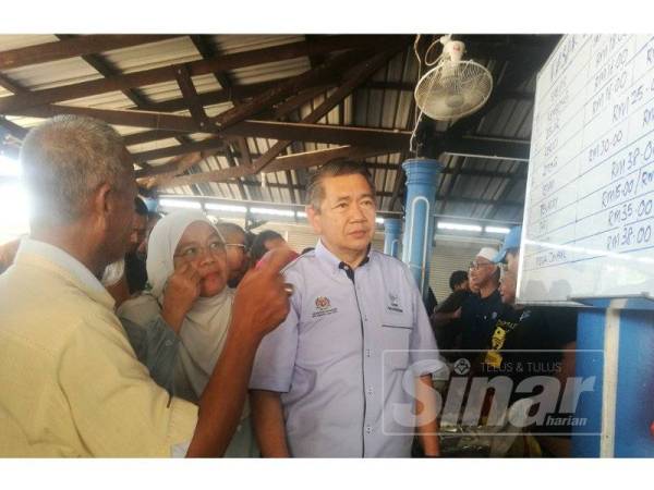 Salahuddin (kanan) diberi penerangan mengenai harga ikan di Pasar Nelayan Balok di sini hari ini.