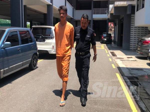 Tertuduh, Wan Aizat Azwan Wan Salleh, 33, (kiri) dikawal polis keluar dari lokap menuju ke Mahkamah Sesyen Kota Bharu, di sini, untuk dihukum atas kesalahan rompakan berkumpulan dan bersenjata parang.