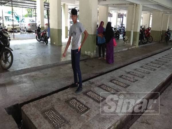 Muhd Amin menunjukkan tempat arwah sahabatnya ditemui selepas terjatuh dari tingkat tujuh bangunan itu, semalam