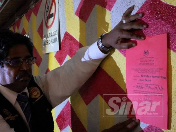 Pegawai Kesihatan Persekitaran, S Mariappan menampal notis arah tutup sebuah restoran di Rasah.